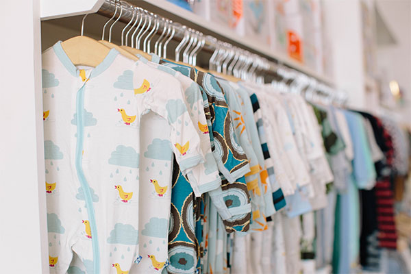 a bunch of baby clothes hanging on a rack.