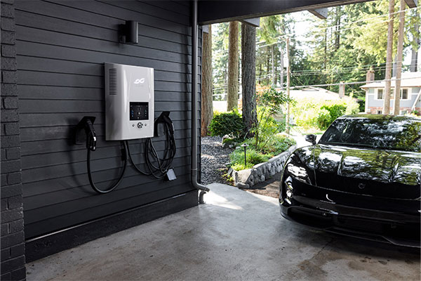 a black car parked in a garage next to an electric charger.