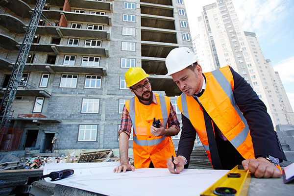 a couple of men standing next to each other on top of a building.