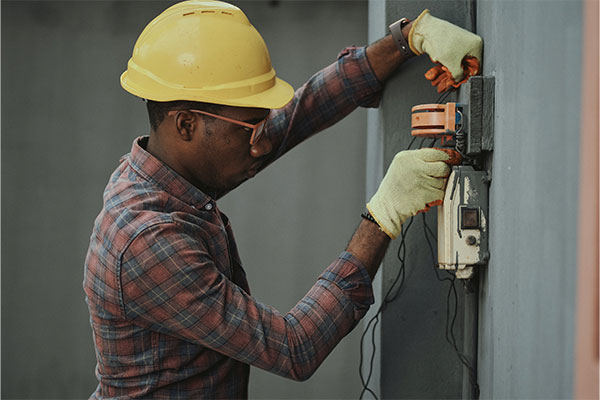 a man wearing a hard hat and safety gloves working on a wall.