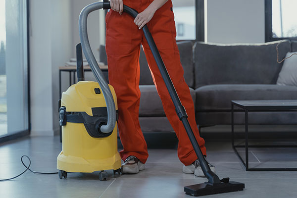 a woman is using a vacuum to clean the floor.