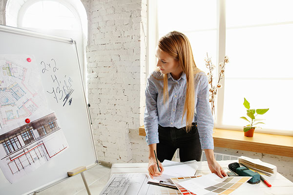 a woman standing in front of a whiteboard with architectural drawings on it.