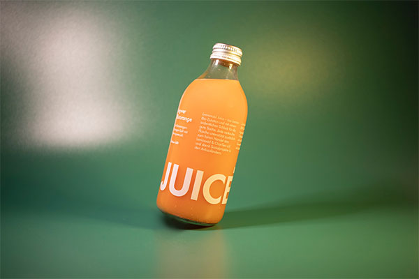 a bottle of juice sitting on a green surface.