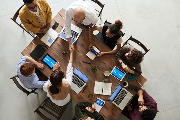 a group of people sitting around a table with laptops.