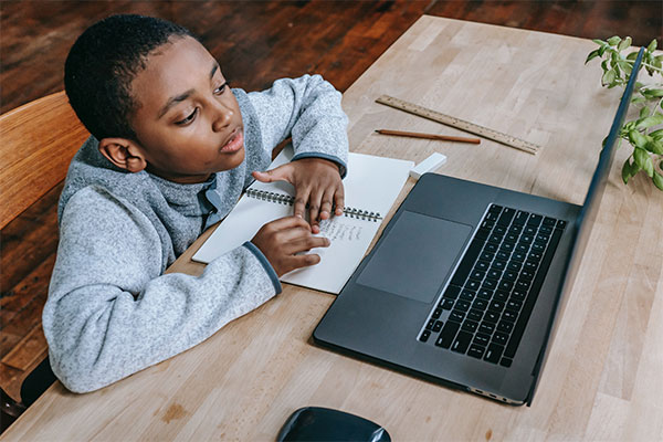 a young boy sitting at a table with a laptop.