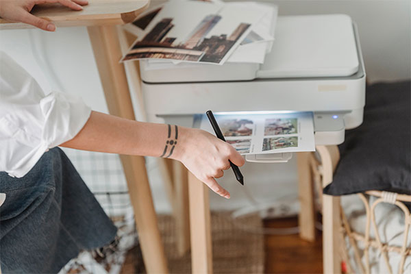 a person holding a piece of paper in front of a printer.