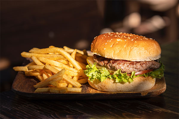 a hamburger and french fries on a wooden tray.