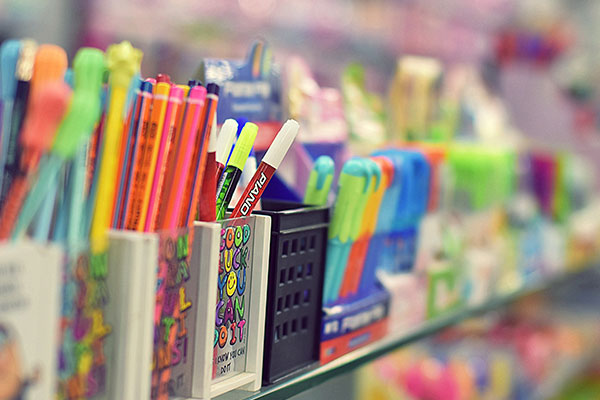 a row of pens and pencils sitting on a shelf.
