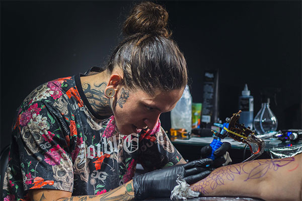 a woman getting a tattoo on her leg.
