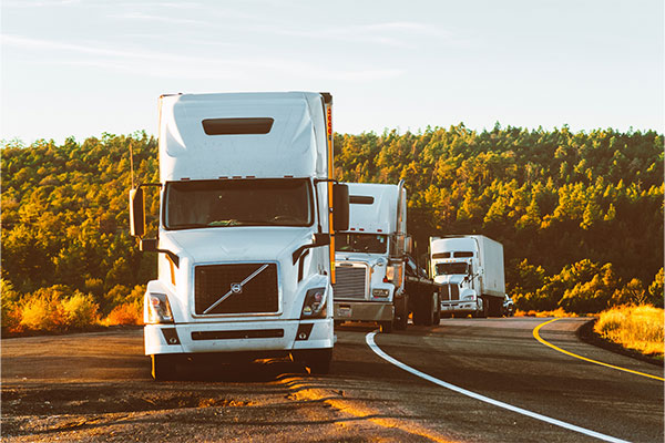 a couple of semi trucks driving down a road.