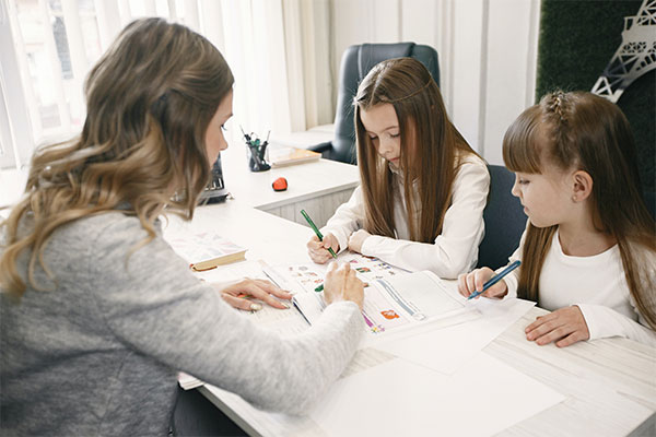 three girls sitting at a table doing homework.